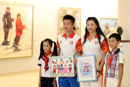 两名手绘画儿童向全运会形象大使张宁（右二）、肇俊哲（左二）献画。