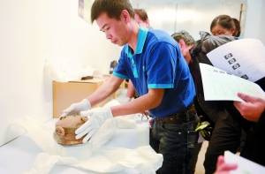 工作人员从封箱中取出香港李郑屋汉墓出土的青黄釉陶鼎